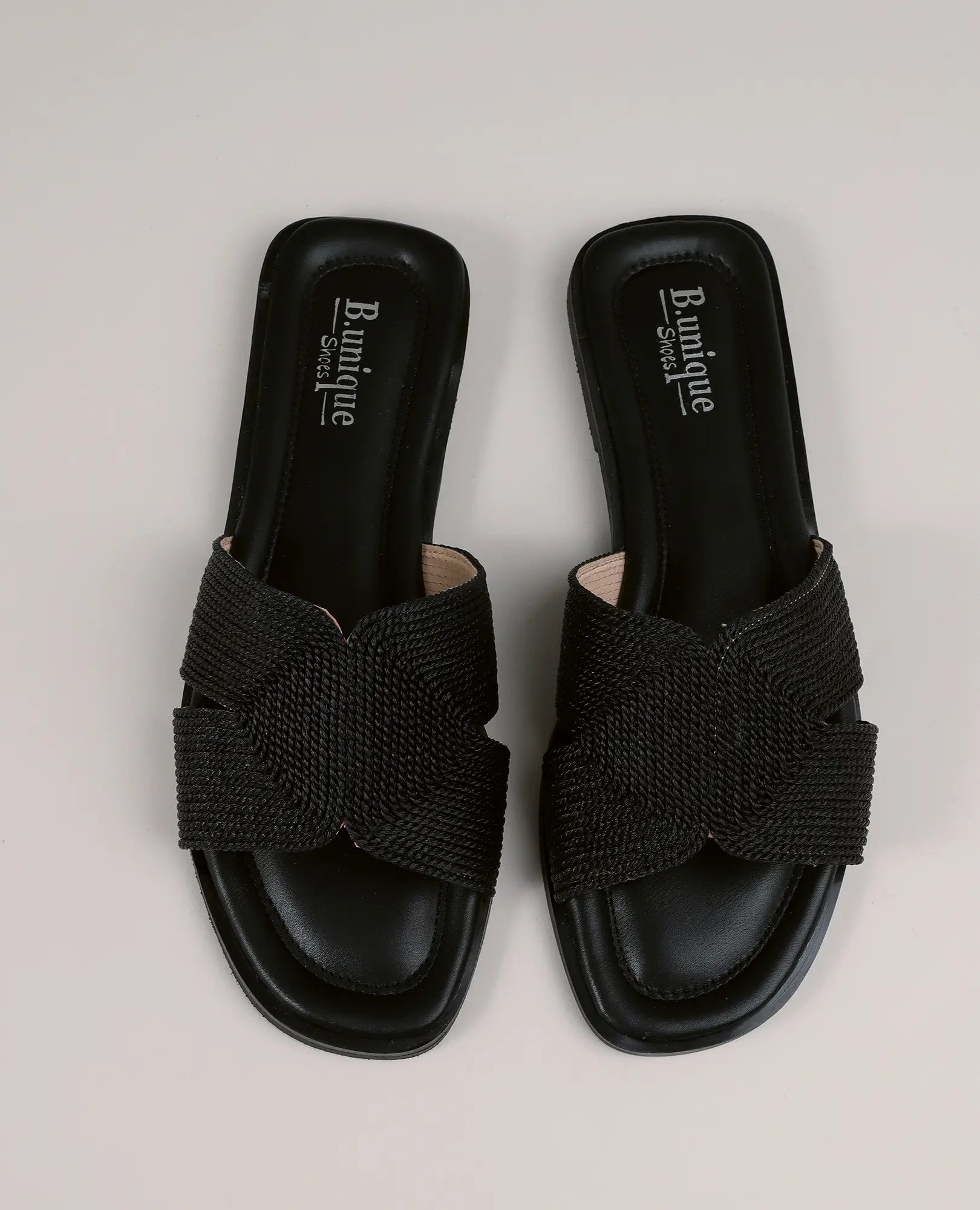 זוג כפכפי רקמה - אלירן מבית B-Unique VEGAN, עם רצועות שזורים בצורת שתי וערב ובקצה מרובע על רקע בהיר.