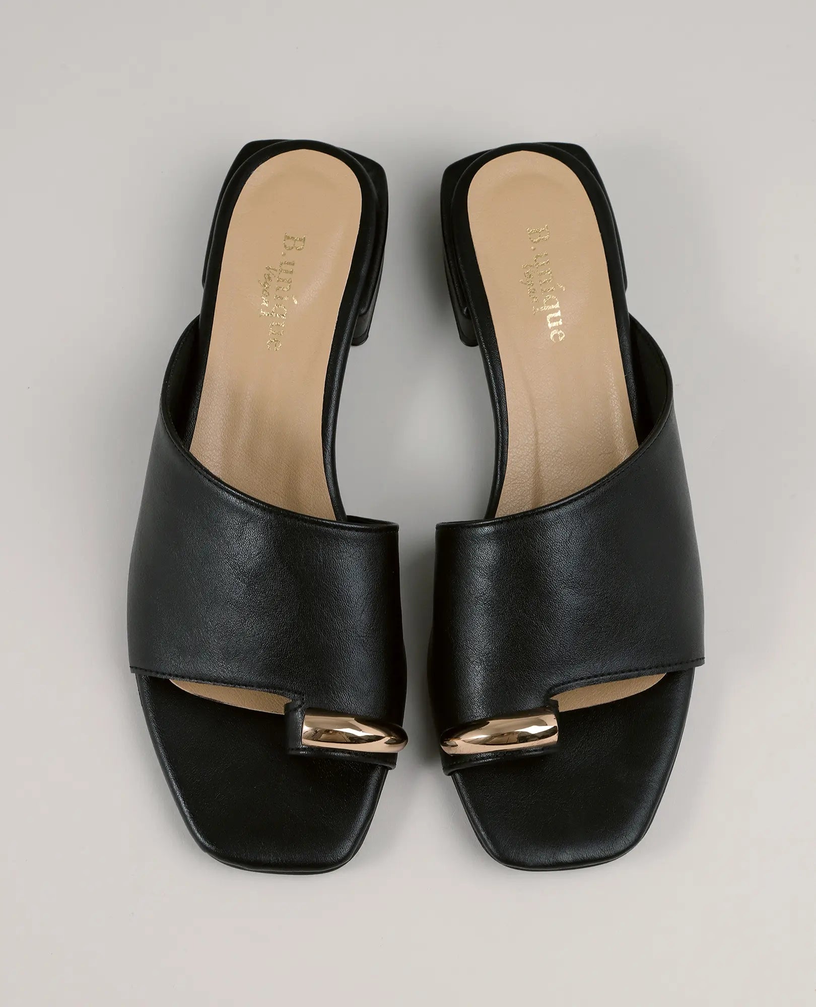 כפכפים עם טבעת - דגם "קארן" של B-Unique VEGAN, דמויי עור בצבע שחור עם עקב מרובע ואלמנט מוזהב, על רקע ניטרלי.