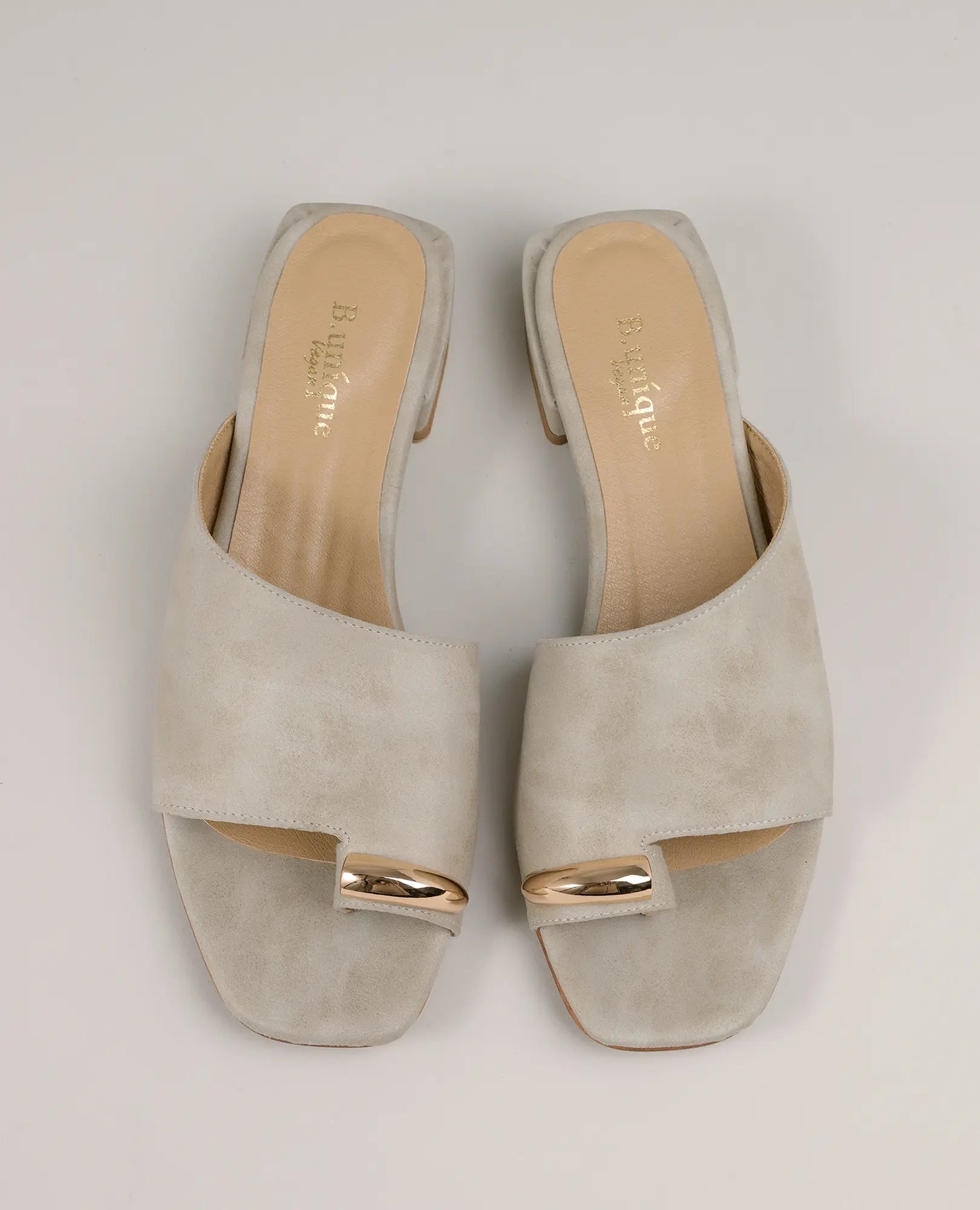 כפכפים עם טבעת קארן של B-Unique VEGAN בצבע אבן, דמוי עור, עם עקב נמוך ועיטורי זהב ברצועות הקדמיות.