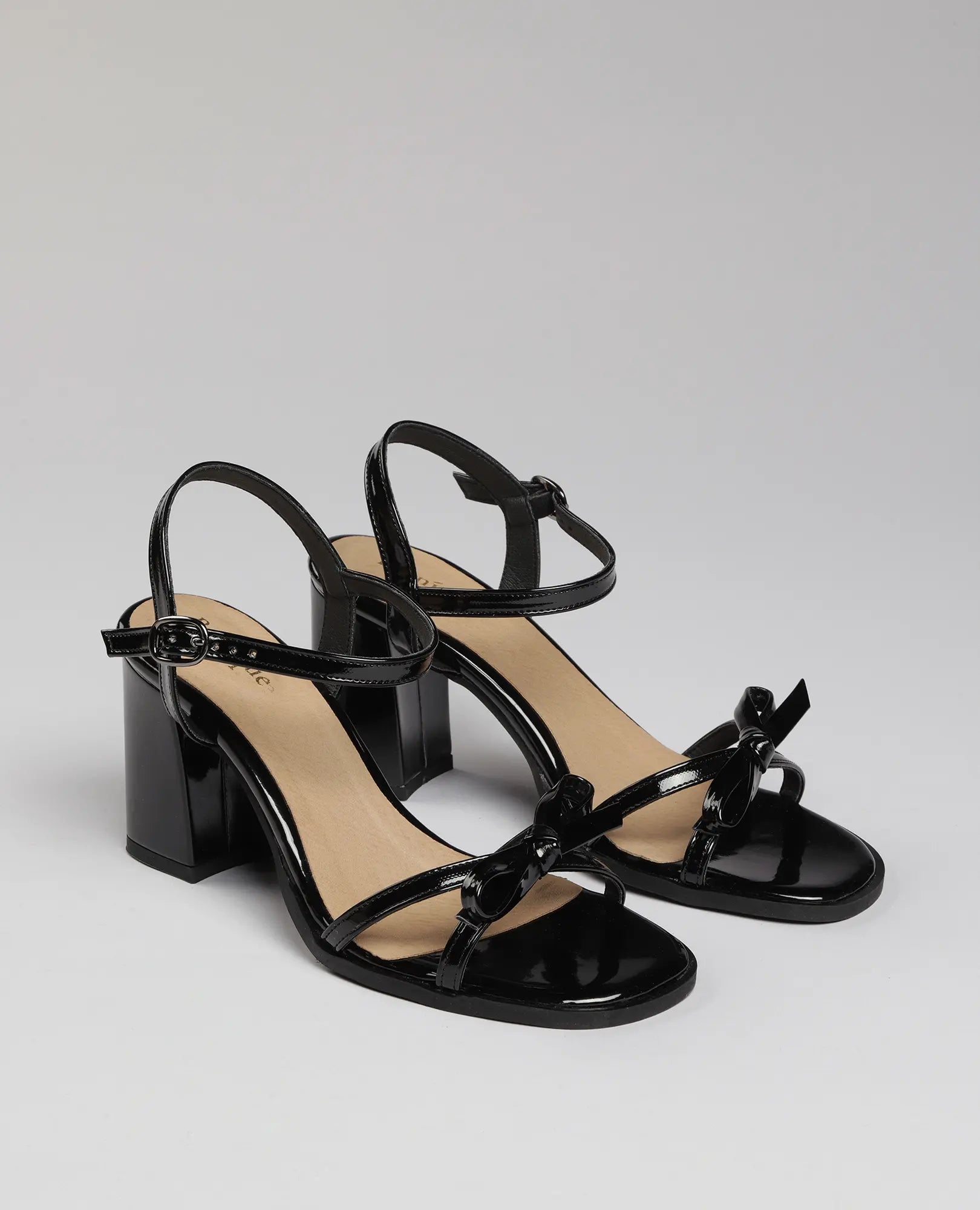 סנדלי עקב עם רצועת פפיון של B-Unique VEGAN בצבע שחור, עם רצועות קרסול ופפיון עדין בחזית.