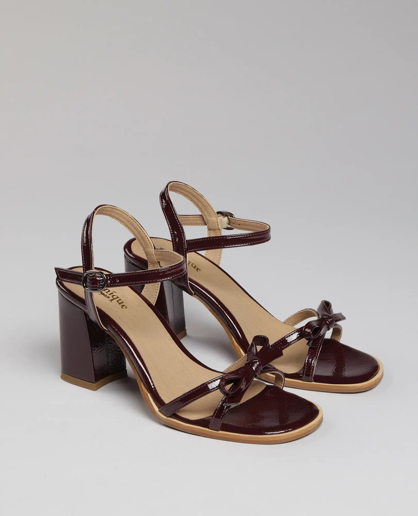 סנדלי עקב עם רצועת פפיון של B-Unique VEGAN: עור דמוי עור בצבע בורדו, רצועות בקרסול ופפיון עדין.
