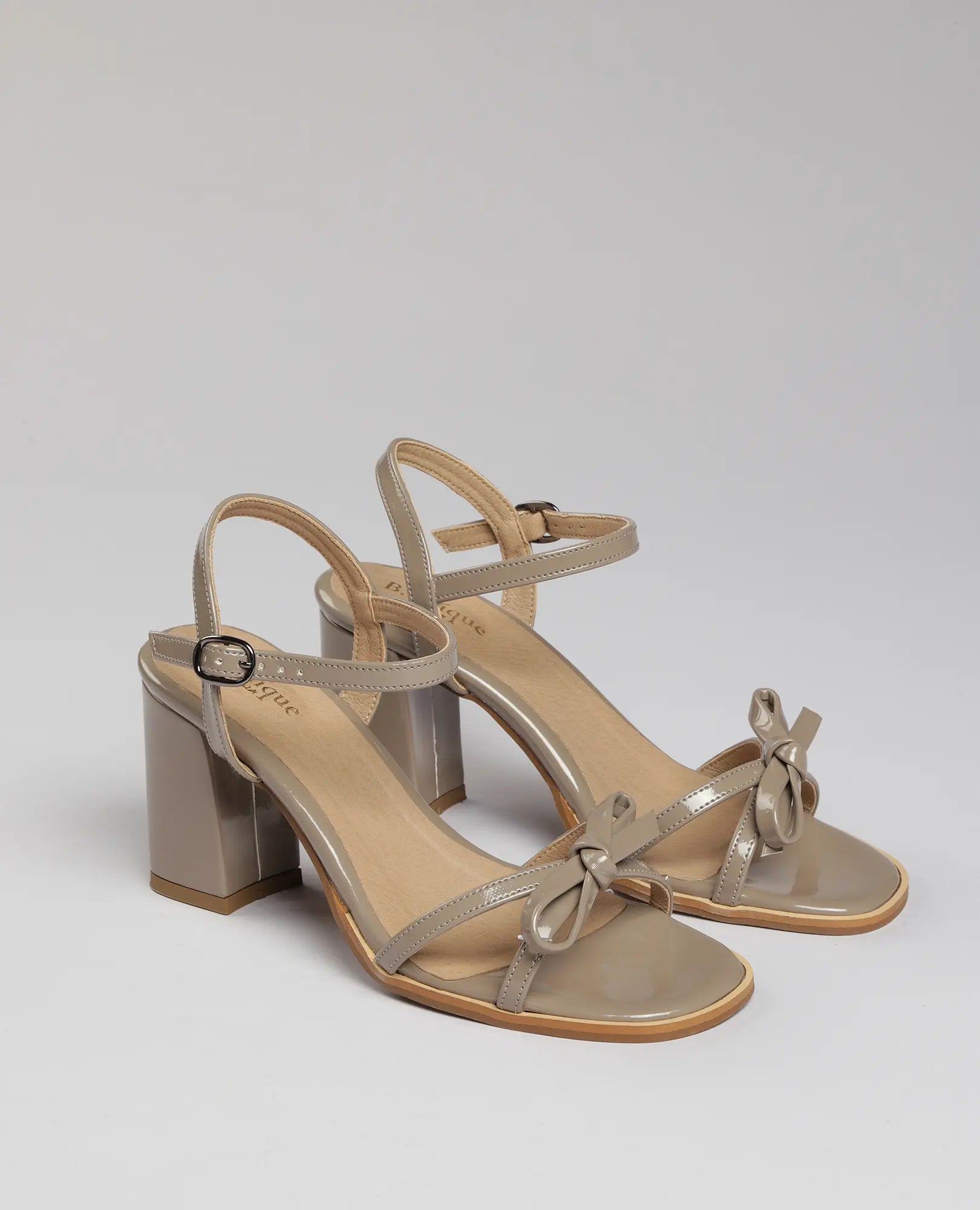 סנדלי עקב עם רצועת פפיון של B-Unique VEGAN, מעור דמוי עור בצבע טאופ, עם פפיון עדין ורצועות קרסול.