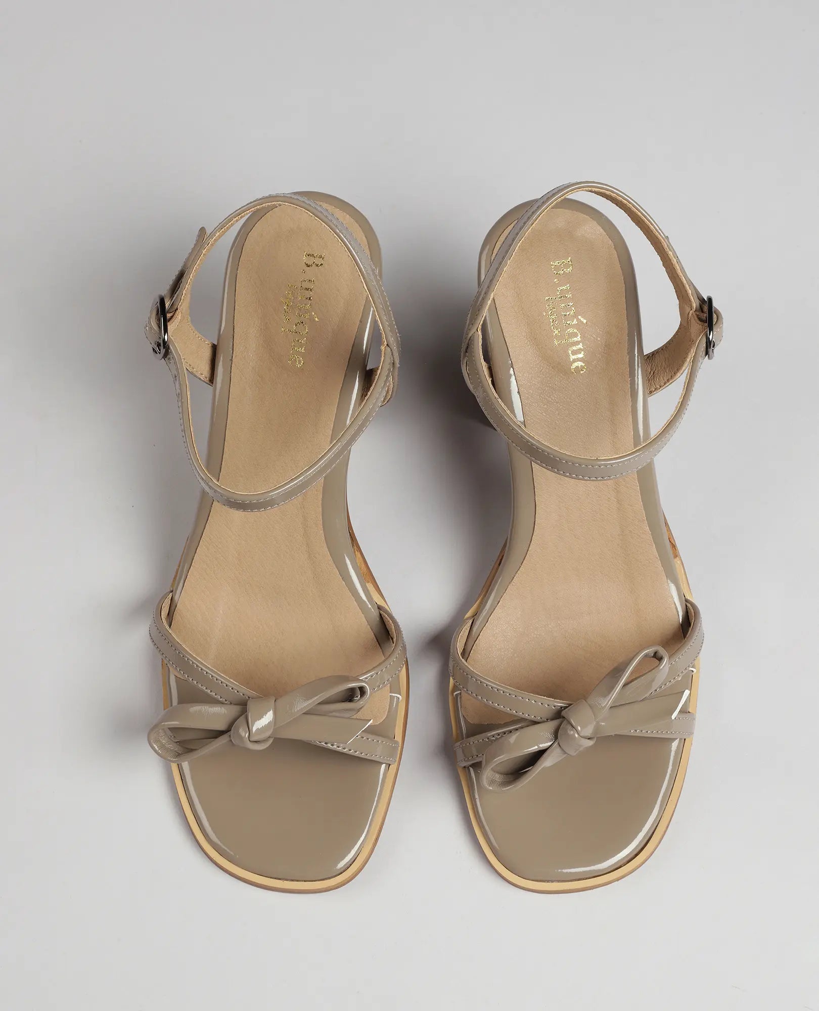 מבט מלמעלה על סנדלי עקב עם רצועת פפיון של B-Unique VEGAN בצבע טאופ, עם קשת עדינה על רקע ניטרלי.