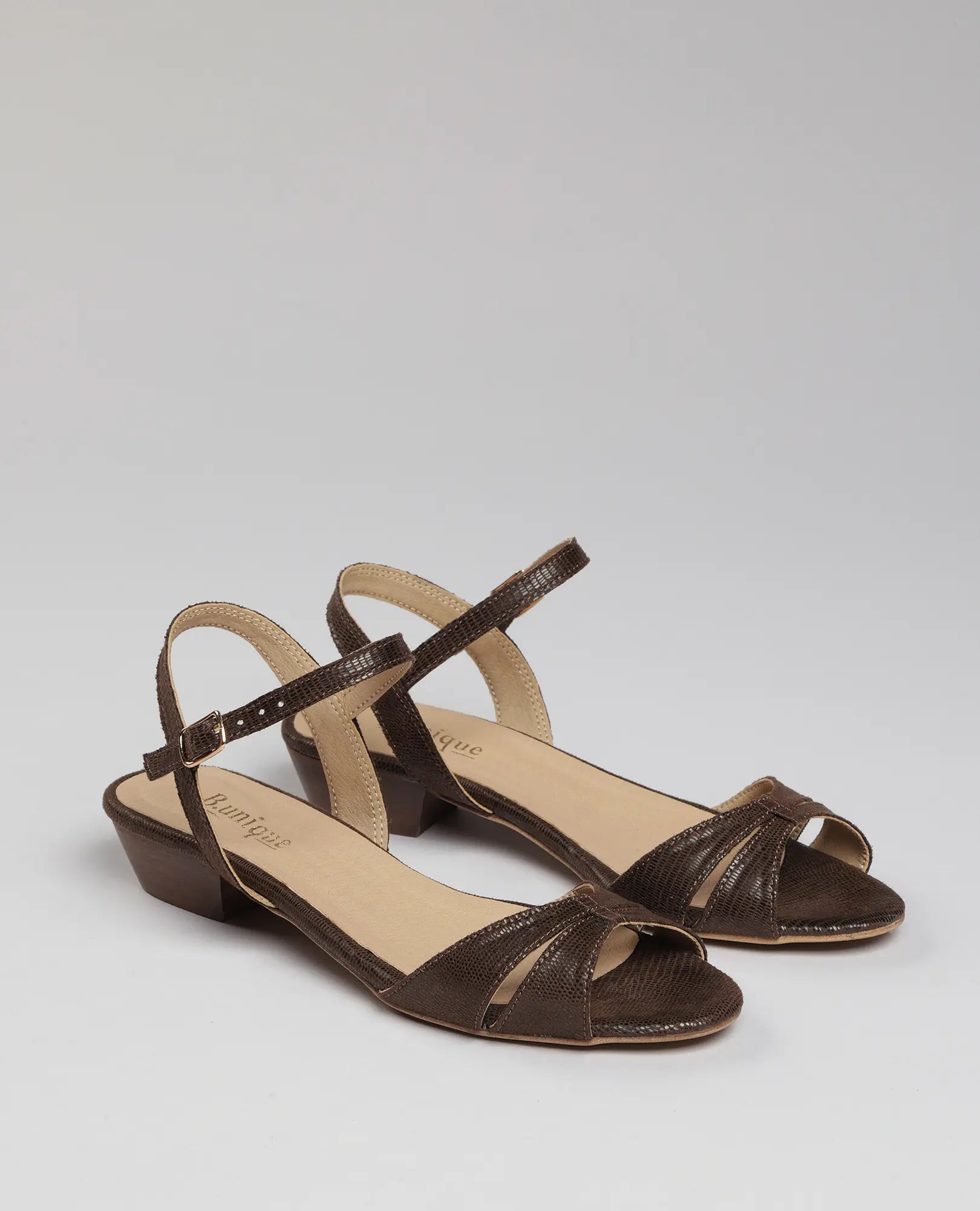 סנדלי רצועות - דגם "לוקי" בצבע חום מבית B-Unique VEGAN, עם עקב נמוך, רצועות בקרסול וסגירת אבזם.