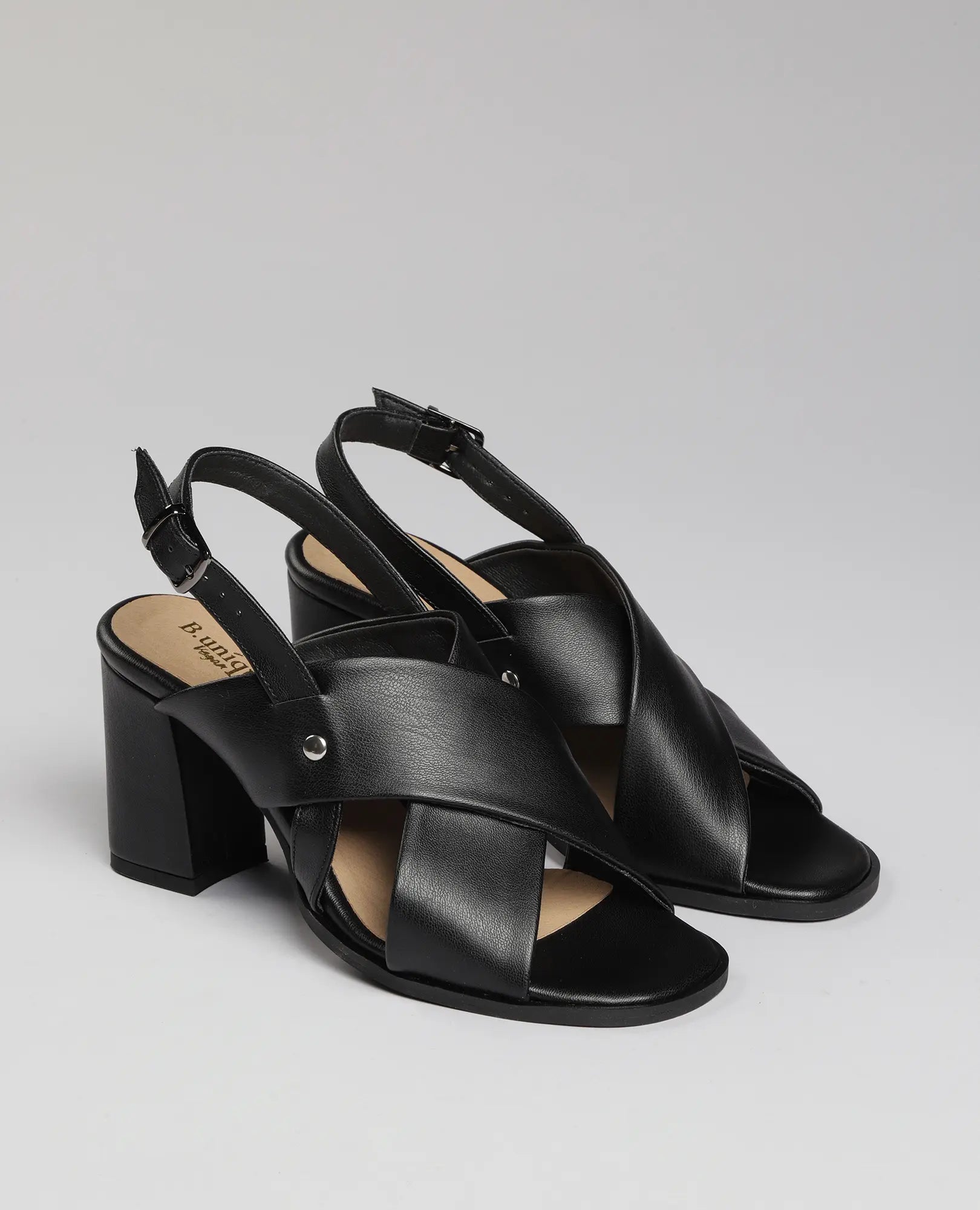 סנדל עקב עם רצועות בצורת X של B-Unique VEGAN, דמוי עור שחור, עם עקב רחב ואבזם בקרסול.