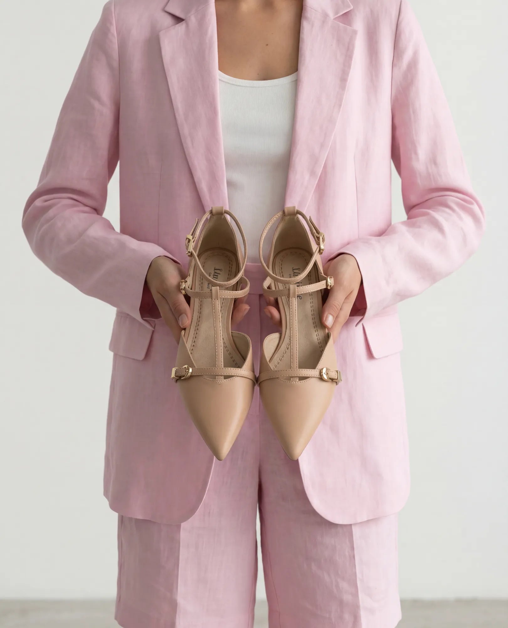 אדם בחליפה ורודה מחזיק נעלי סירה - אושר על ידי B-Unique VEGAN.