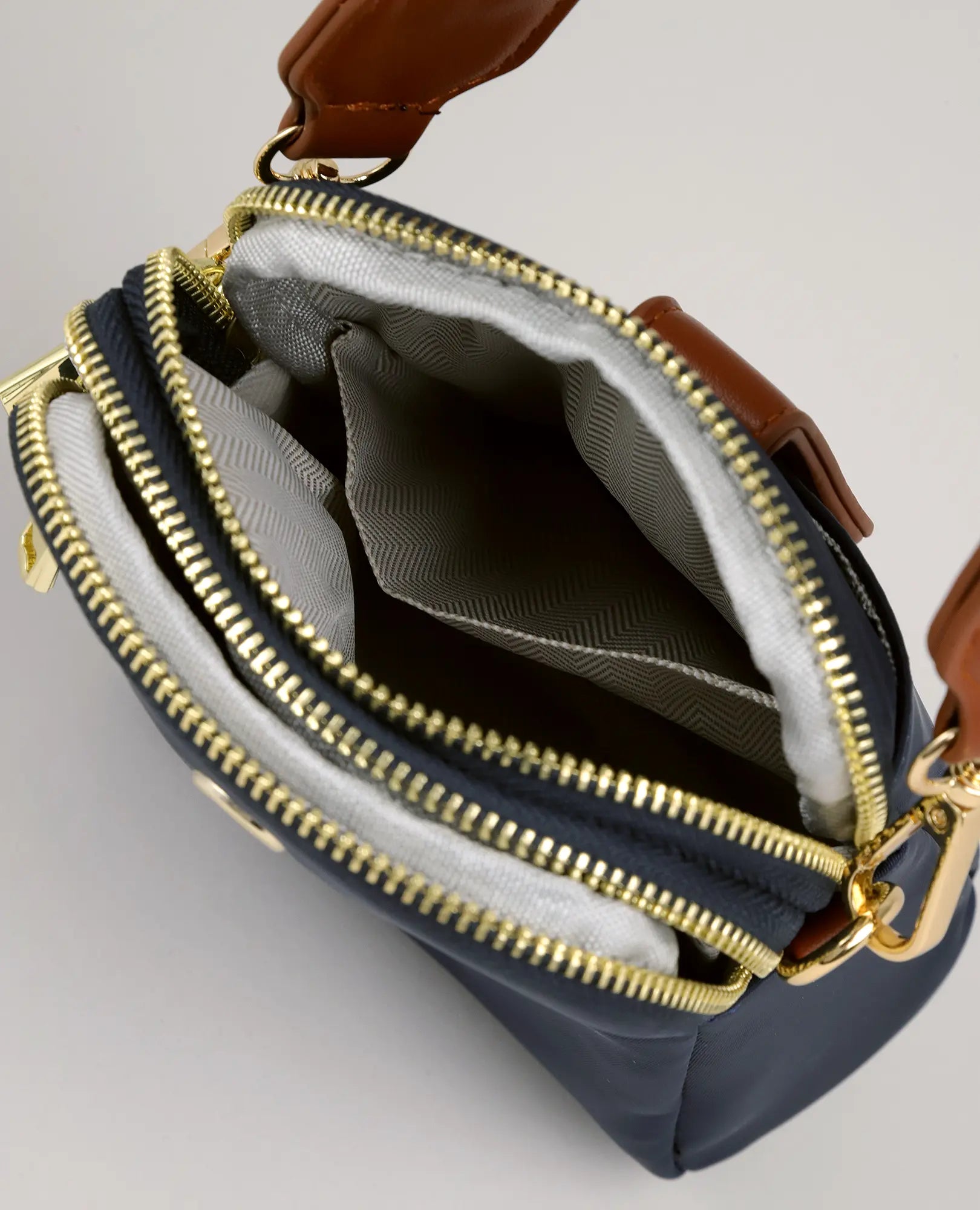 תיק צד למחשב נייד - "לונה" מבית B-Unique Bags, עשוי מניילון עם רוכסנים מוזהבים, ידיות חומות ובטנה בדוגמה אפורה, מוצג במצב פתוח.