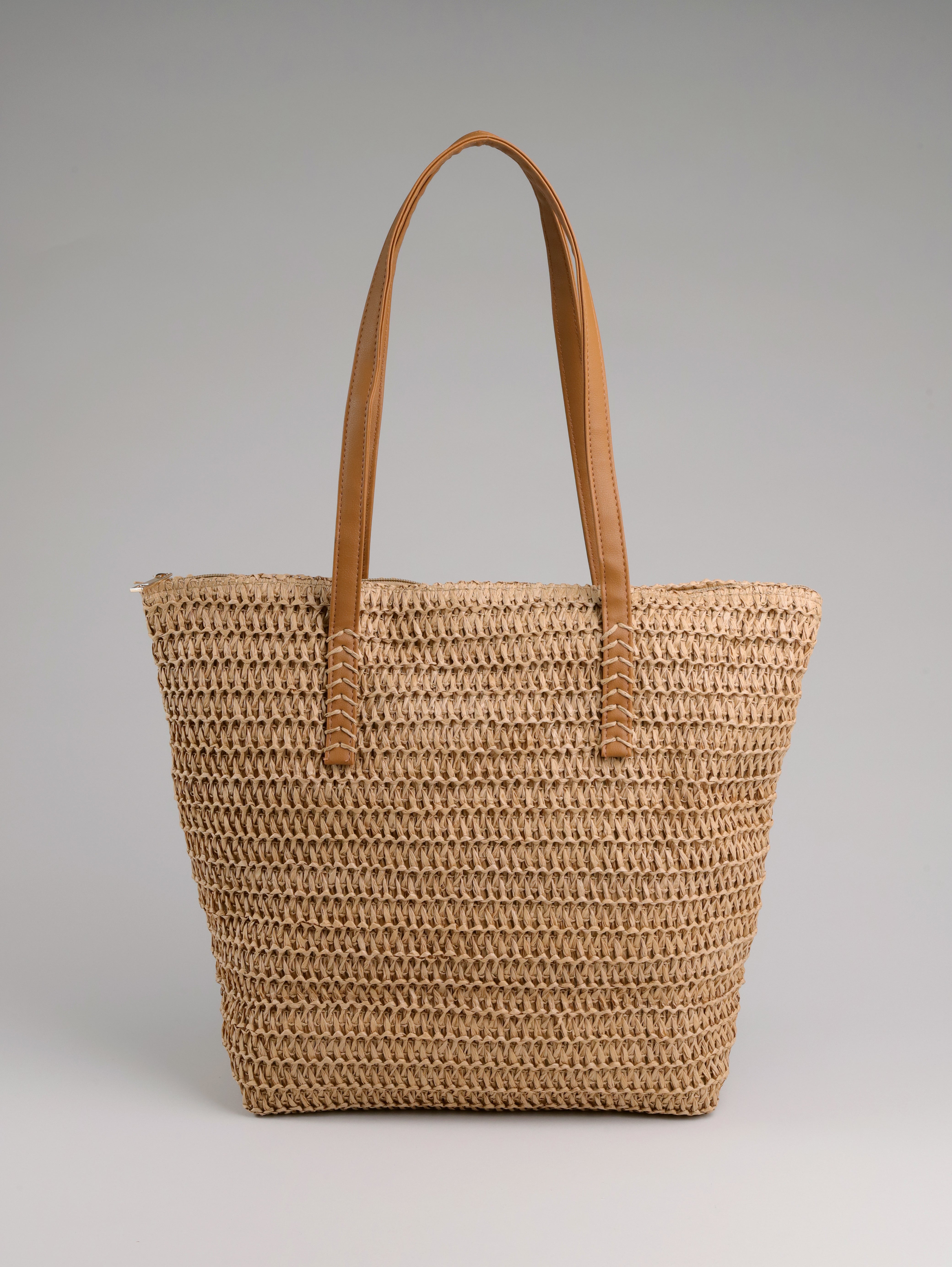 תיק קש של B-Unique Bags עם ידיות עור חומות, מושלם לנעליים אופנתיות, מוצג על רקע אפור בהיר.