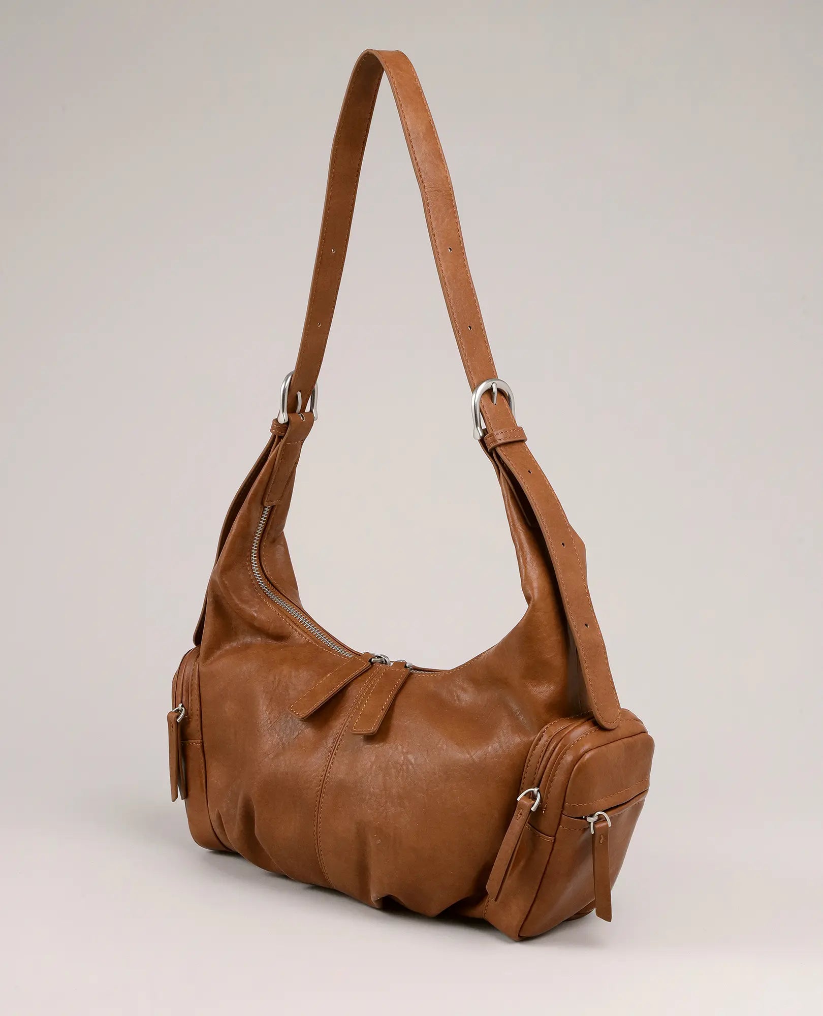 תיק צד-דור של B-Unique Bags, דמוי עור חום עם כיסים צדדיים ורוכסן, מוצג על רקע חלק.