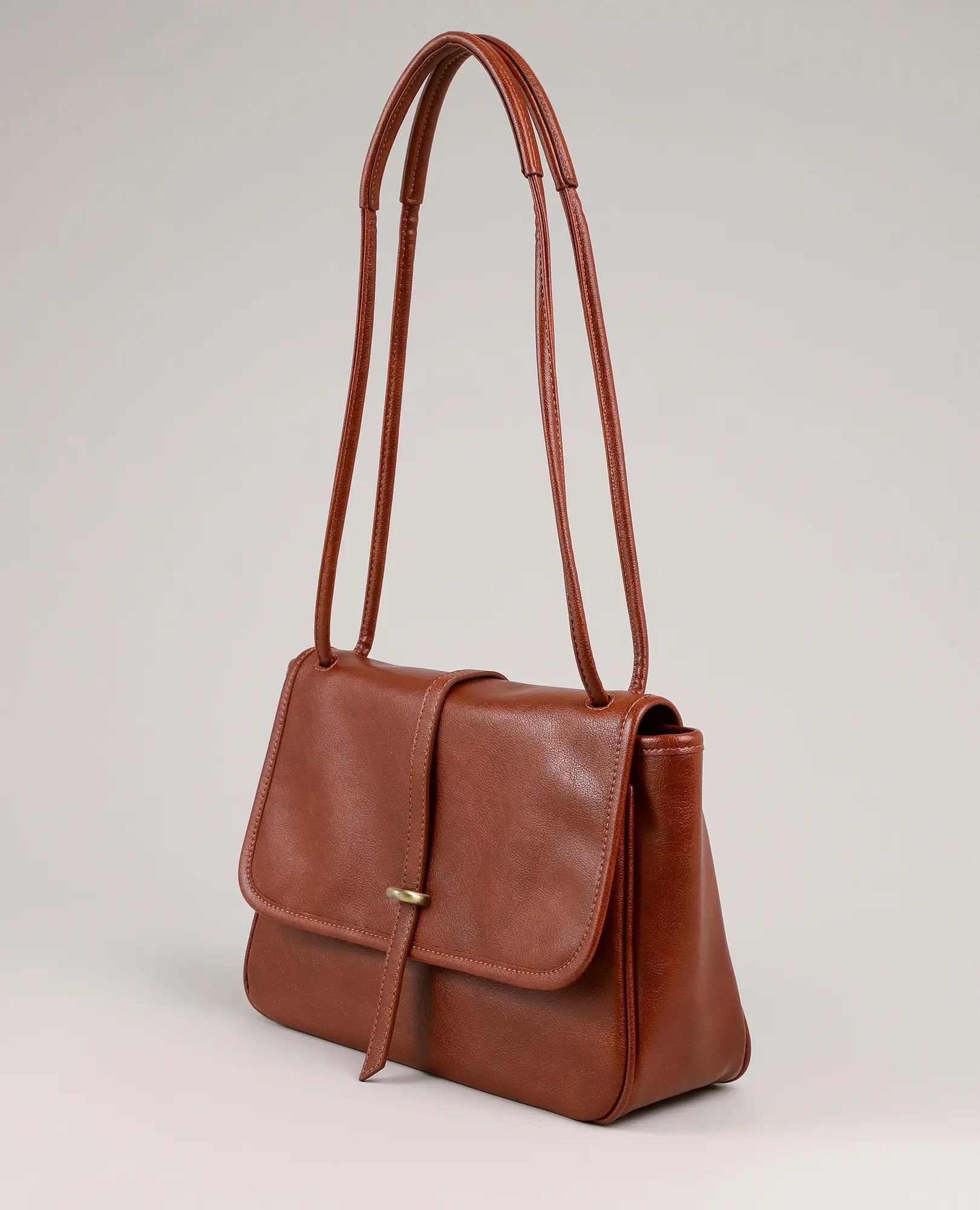 תיק צד חום עם אבזם טבעת קדמי מבית B-Unique Bags, עם שתי רצועות ארוכות, סגירת דש ועיצוב מינימליסטי.