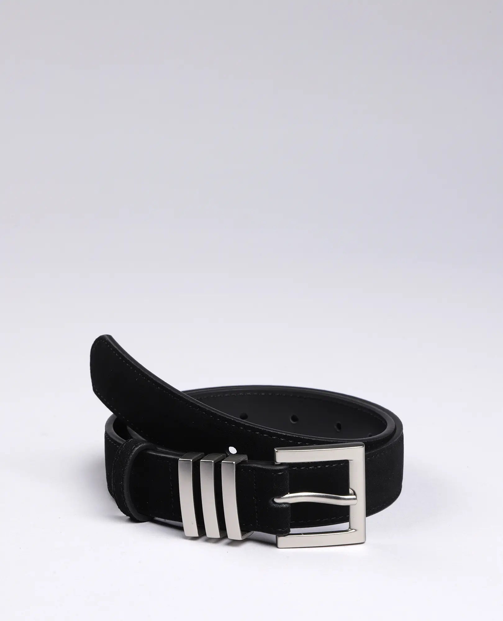 חגורת עור בצבע שחור של B-Unique Bags עם אבזם כסף מונחת מגולגלת על רקע לבן.