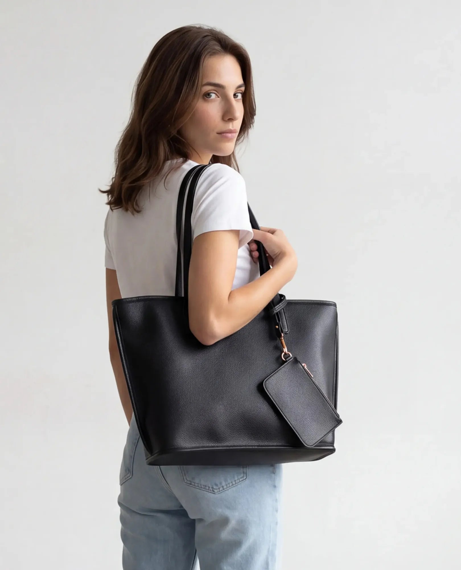 אישה מחזיקה תיק צד גדול עם ארנק "רומא" של B-Unique Bags, ומביטה מעבר לכתפה.