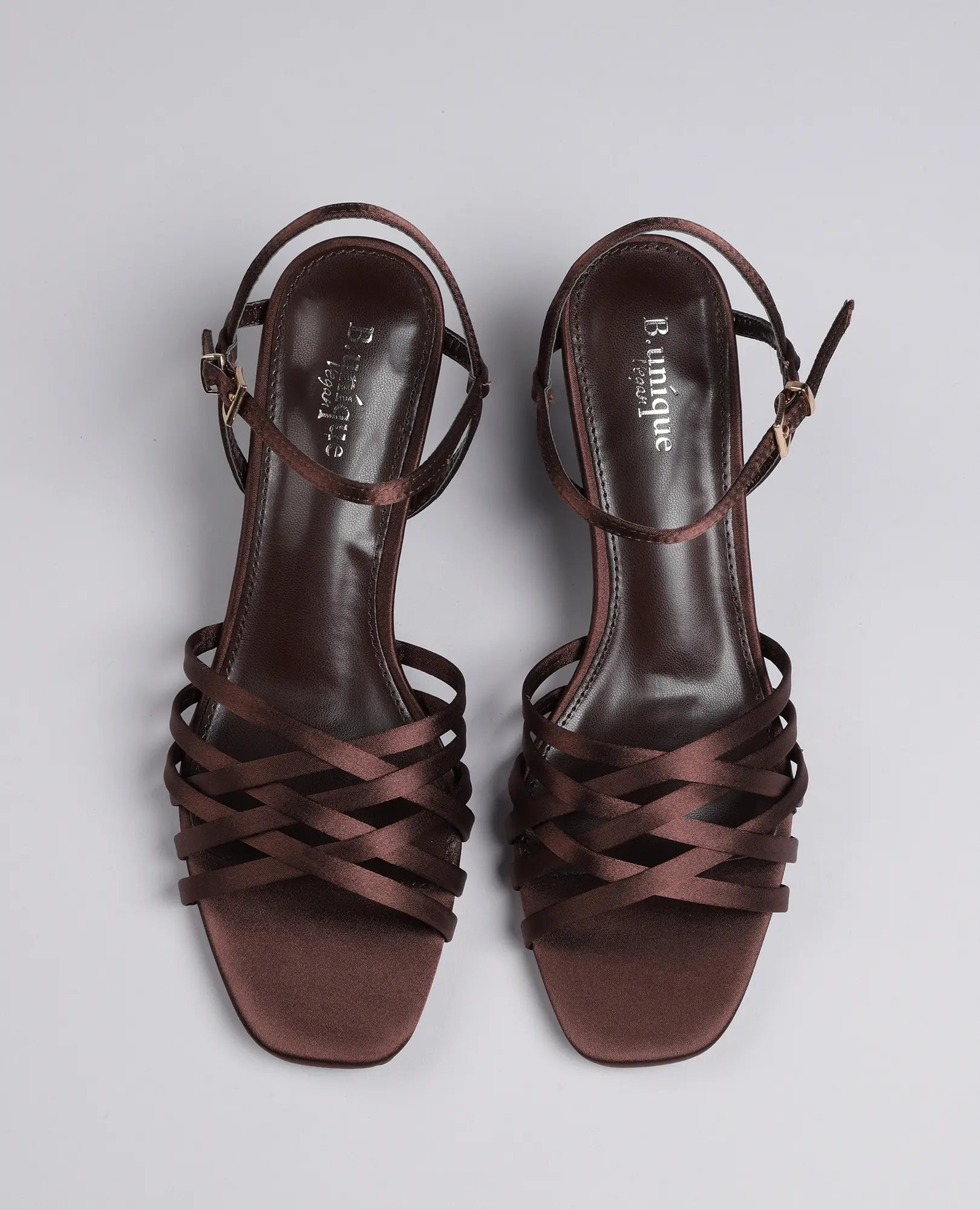 זוג סנדלי עקב "ברקת" מבית B-Unique VEGAN בצבע חום, עם רצועות בקרסול וקצה מרובע, מצולמים מלמעלה על רקע אחיד.