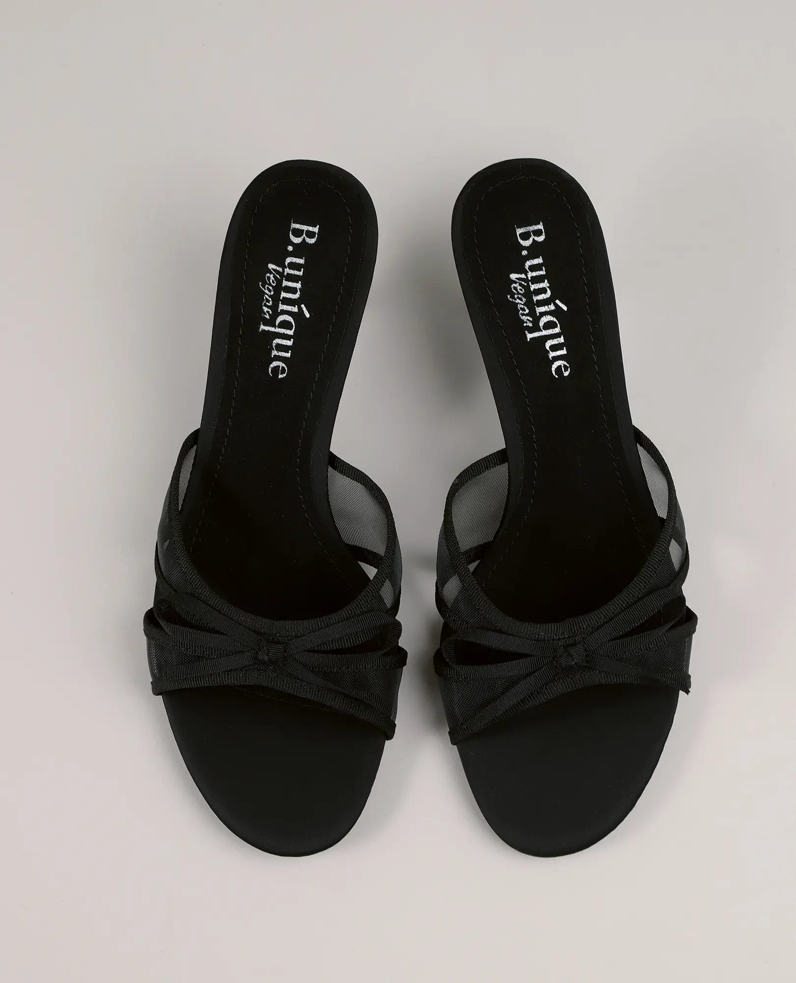 כפכפי עקב - כפכפים שחורים עם רצועות דקות, פפיון והכיתוב B-Unique VEGAN על הסוליה.