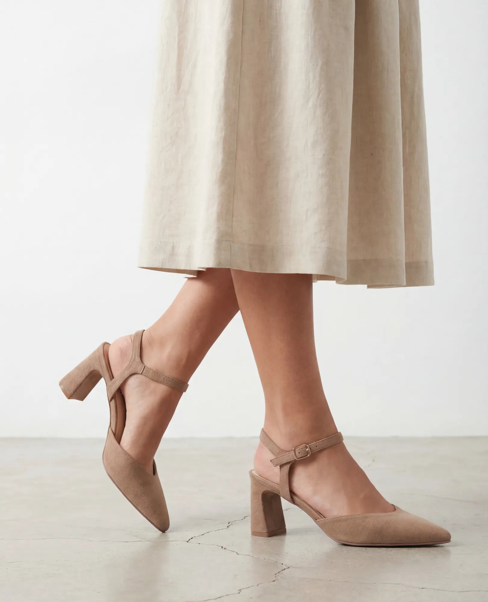 אישה לבושה בחצאית בצבע בז' ונעלי עקב B-Unique VEGAN - ארין עומדת על רצפה בהירה.