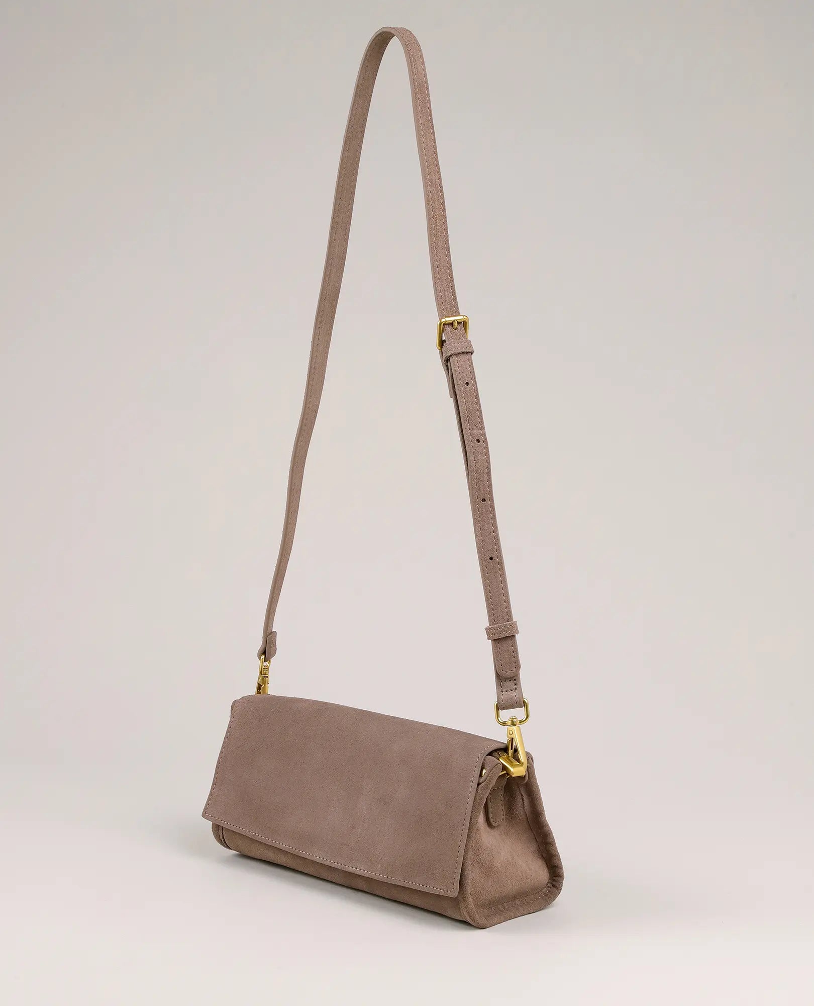 תיק צד מעור נילי מבית B-Unique Bags עם רצועה מתכווננת ואלמנטים ממתכת מוזהבים, על רקע בהיר.