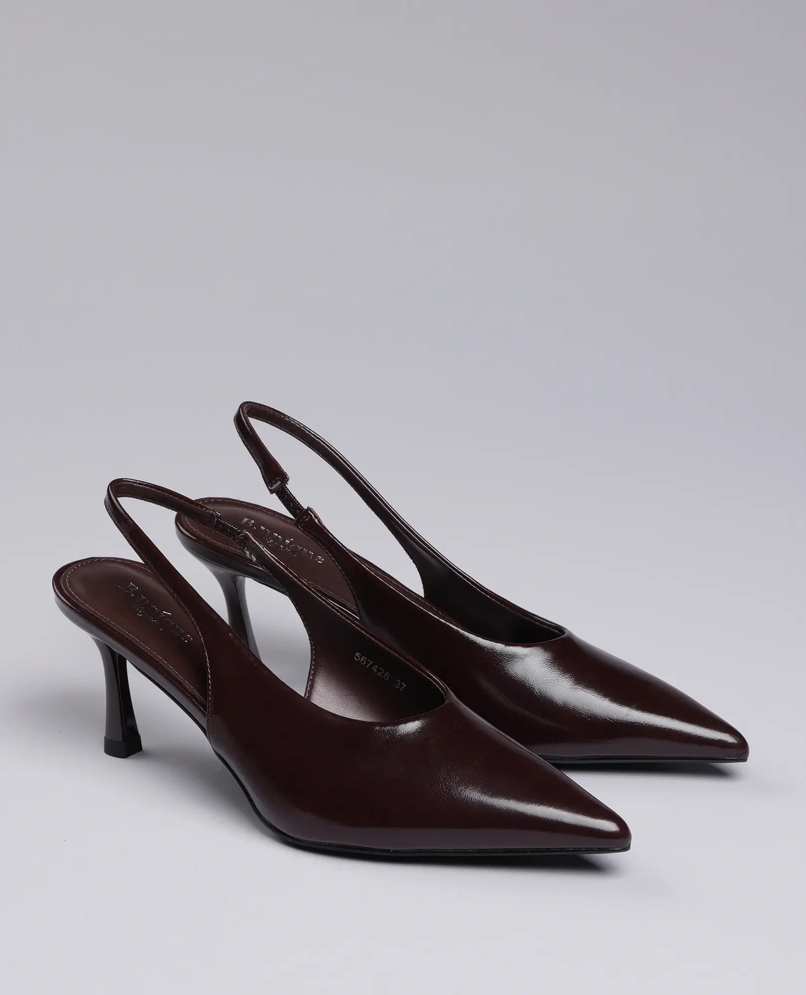 זוג נעלי עקב בורדו שפיץ- דורון מבית B-Unique VEGAN עם קצות מחודדים ועקבים נמוכים על רקע אפור אחיד.