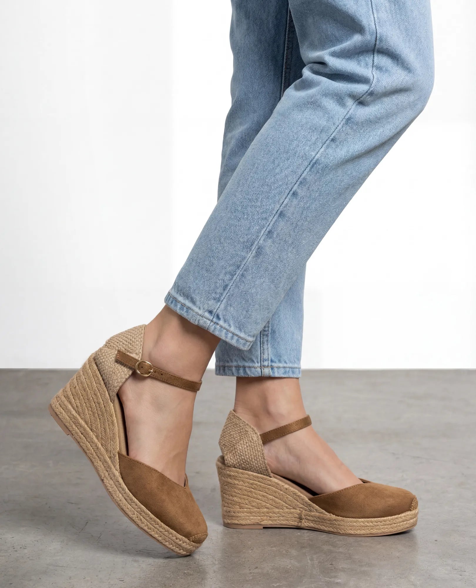 אדם לבוש בג'ינס תכלת ונעלי פלטפורמה בצבע קאמל מבית B-Unique VEGAN, עומד על רצפה אפורה.