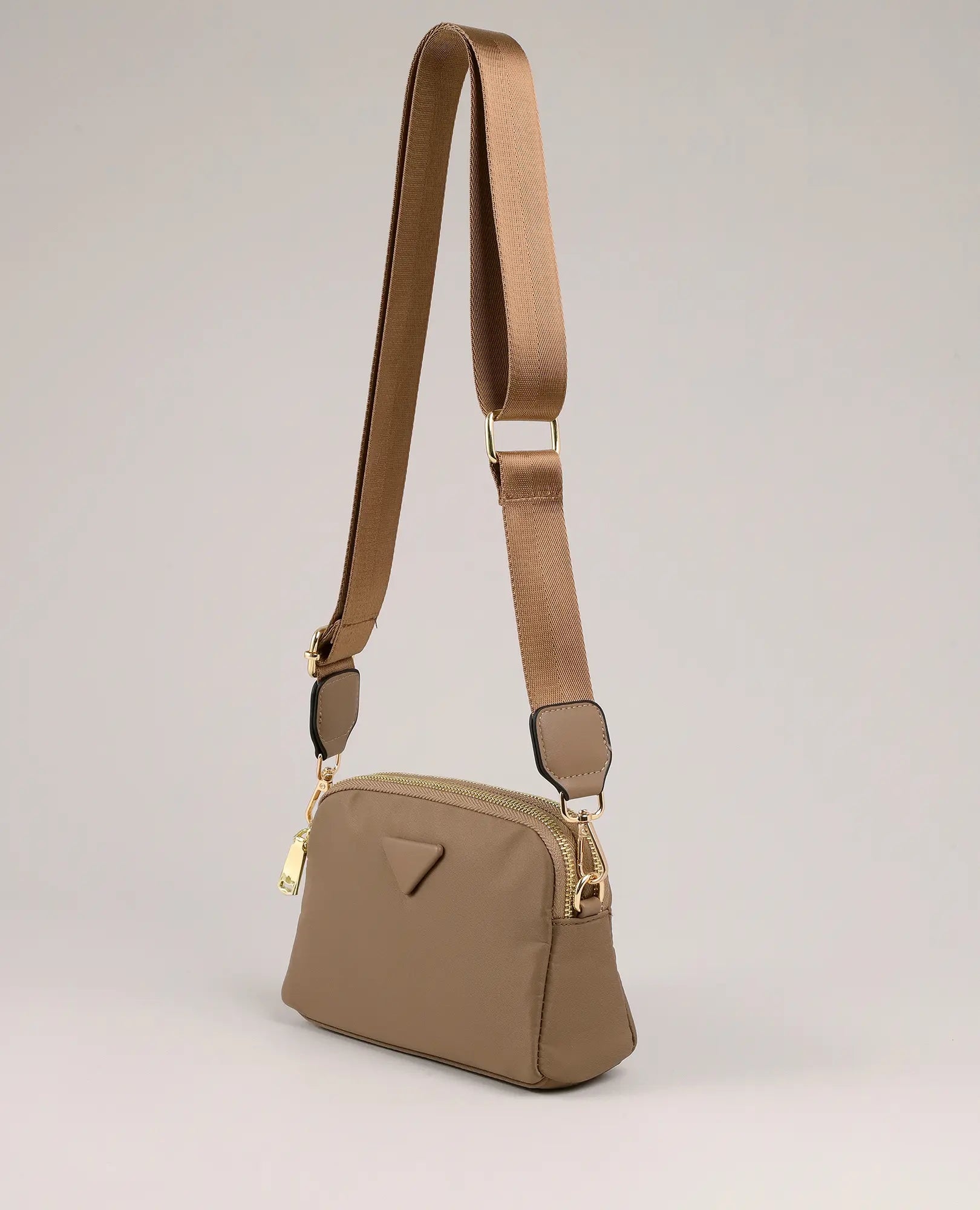 תיק צד קטן של ויקטוריה בצבע חום בהיר עם אבזמי זהב ורצועה רחבה מבית B-Unique Bags על רקע בהיר.